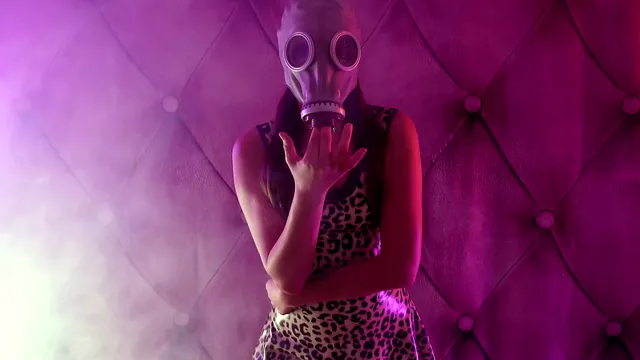 Lesbian femdom play in glossy latex, a gas mask and drifting smoke